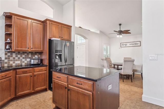 kitchen with a center island, stainless steel refrigerator with ice dispenser, ceiling fan, light tile patterned floors, and tasteful backsplash