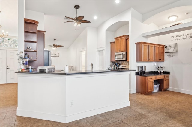 kitchen featuring kitchen peninsula, ceiling fan with notable chandelier, stainless steel appliances, and high vaulted ceiling