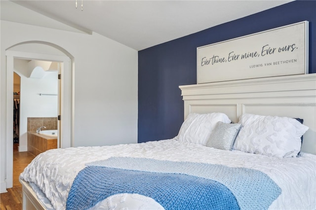 bedroom with connected bathroom and hardwood / wood-style flooring