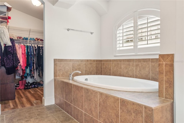 bathroom featuring a relaxing tiled tub, tile patterned floors, and lofted ceiling