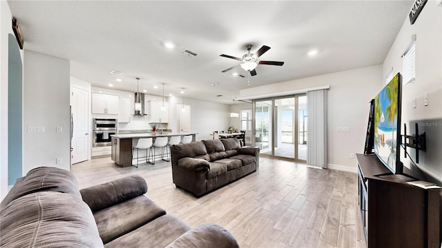 living room with ceiling fan, light hardwood / wood-style flooring, and sink