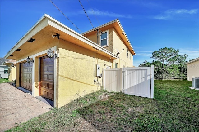 view of side of home featuring a yard, a garage, and central AC unit