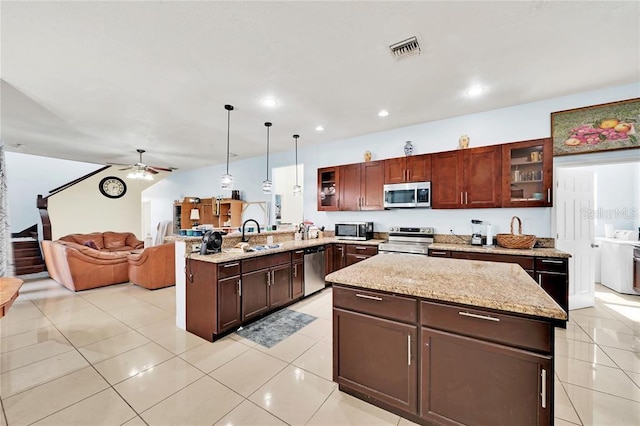 kitchen with kitchen peninsula, light tile patterned floors, pendant lighting, and appliances with stainless steel finishes