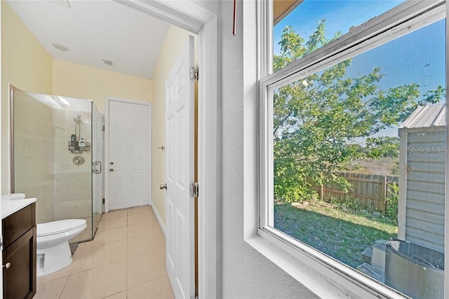 bathroom featuring toilet, vanity, tile patterned floors, and a shower with door