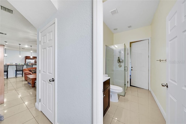 bathroom with tile patterned flooring, vanity, toilet, and a shower with shower door