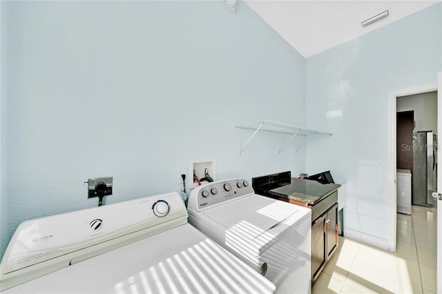 laundry area with washer and clothes dryer and light tile patterned floors