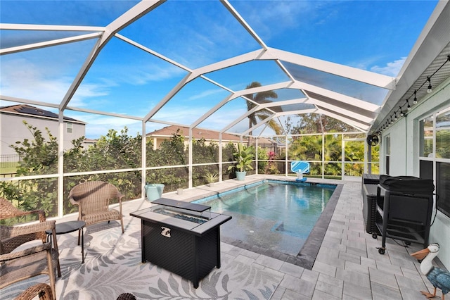 view of pool with a fire pit, glass enclosure, and a patio area