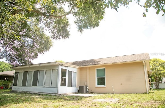 rear view of house featuring a sunroom, cooling unit, and a yard