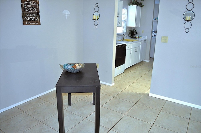 kitchen with light tile patterned floors, electric range oven, and white cabinets