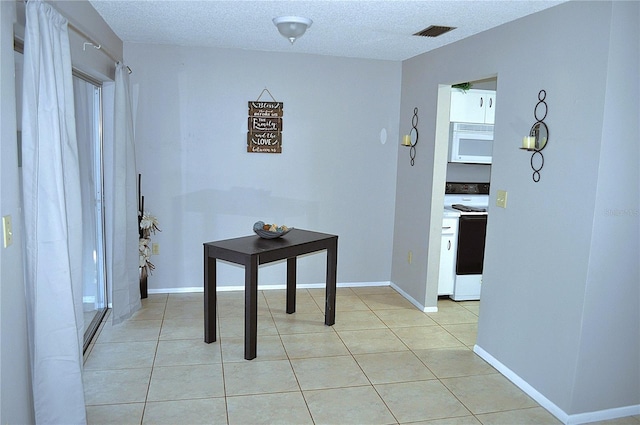 hall with light tile patterned flooring and a textured ceiling