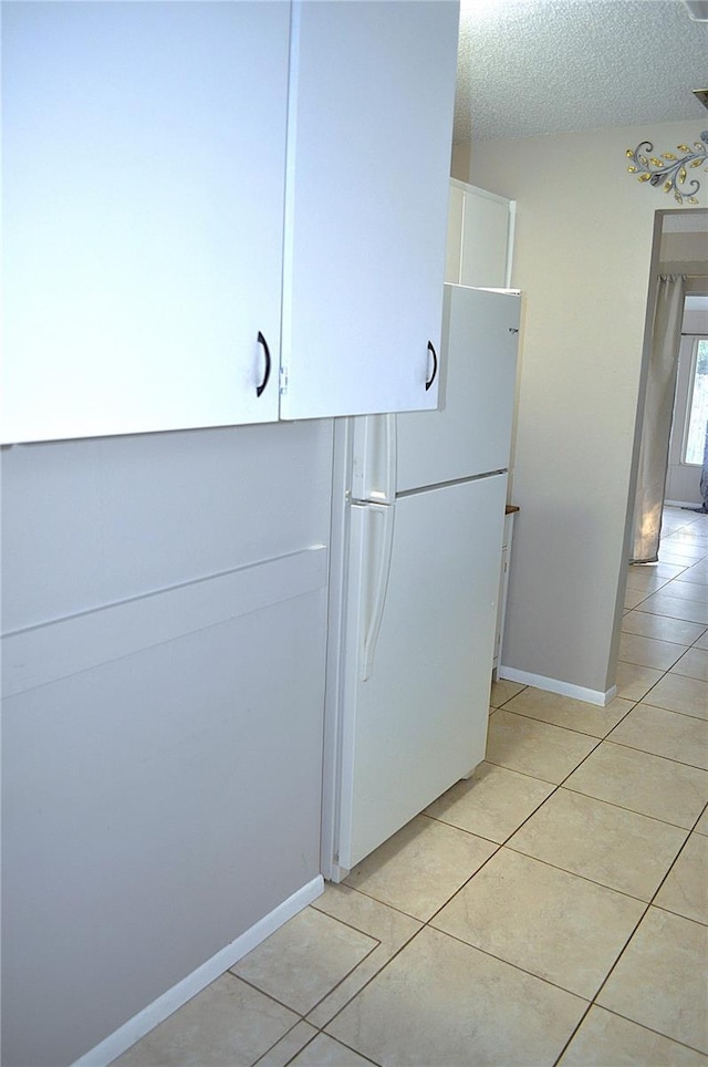 kitchen featuring light tile patterned floors, a textured ceiling, and white fridge