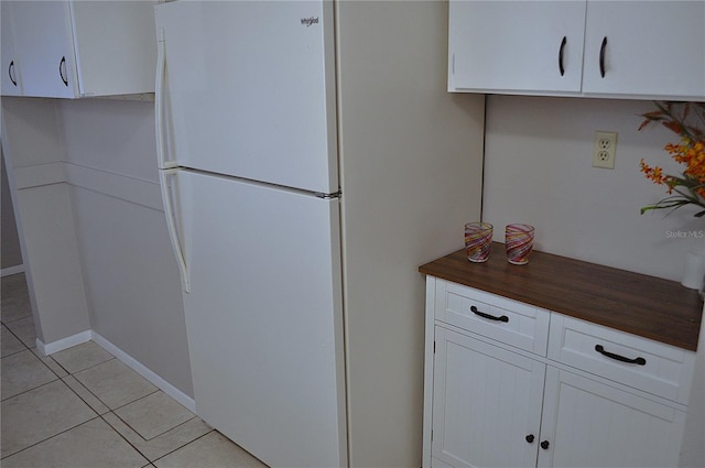 kitchen with light tile patterned floors, white cabinets, and white refrigerator