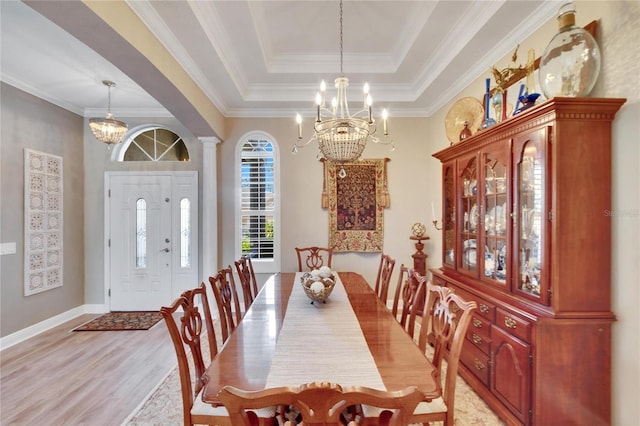 dining room with a tray ceiling, light hardwood / wood-style floors, a notable chandelier, and ornamental molding