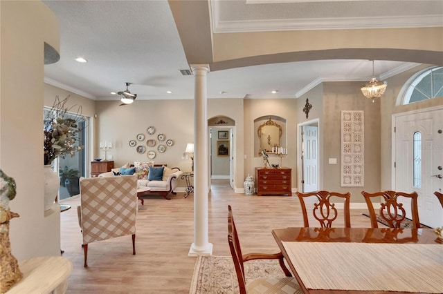 dining area with ceiling fan with notable chandelier, ornate columns, crown molding, and light hardwood / wood-style flooring