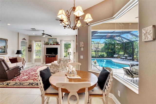 tiled dining room featuring ceiling fan with notable chandelier and plenty of natural light