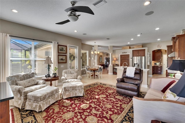 living room featuring a textured ceiling and ceiling fan with notable chandelier