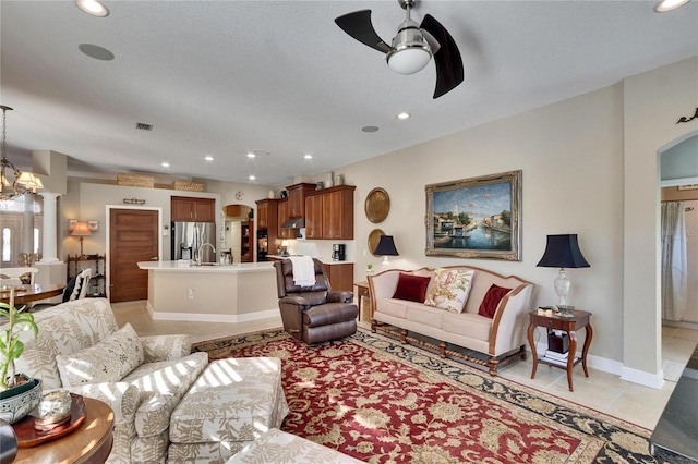 tiled living room featuring ceiling fan with notable chandelier