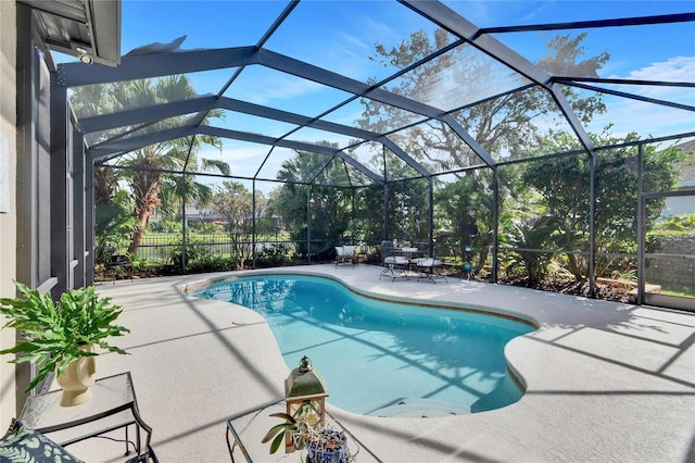 view of pool with glass enclosure and a patio