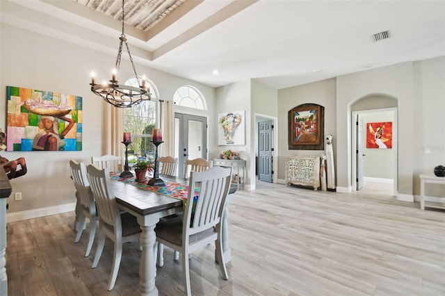 dining area with french doors, light hardwood / wood-style flooring, and a notable chandelier