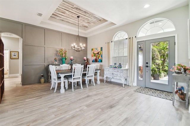 dining room featuring a chandelier, light hardwood / wood-style floors, and a tray ceiling