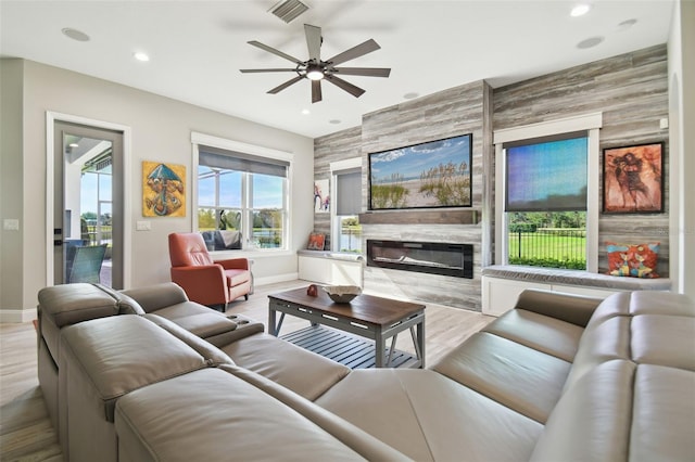 living room with light hardwood / wood-style flooring, ceiling fan, and a premium fireplace