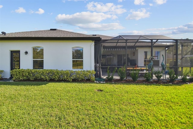 rear view of house featuring a lawn and glass enclosure