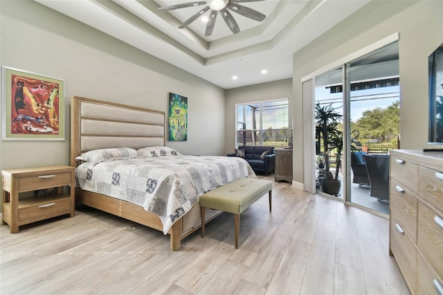 bedroom featuring light wood-type flooring, access to outside, ceiling fan, and a tray ceiling