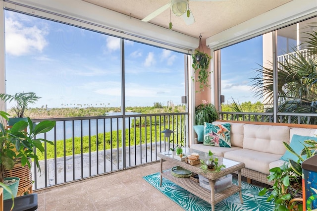 sunroom with ceiling fan and a water view