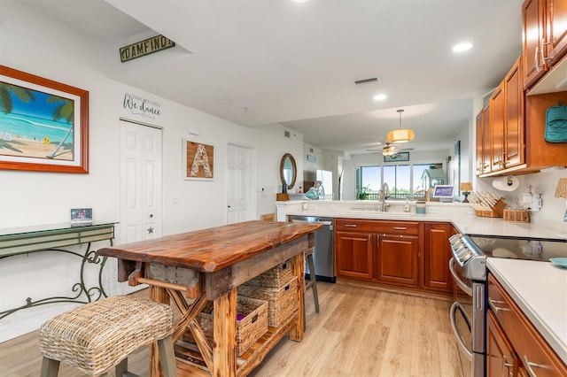 kitchen featuring sink, ceiling fan, light hardwood / wood-style floors, kitchen peninsula, and stainless steel appliances