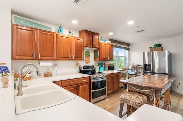 kitchen with appliances with stainless steel finishes, light wood-type flooring, and sink