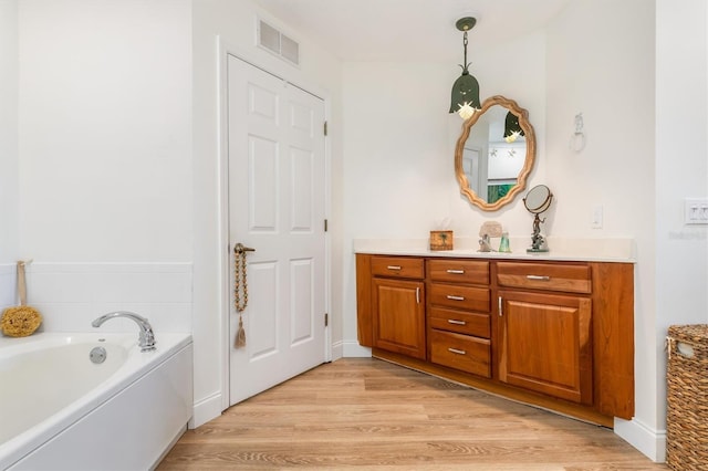 bathroom with vanity, a bath, and hardwood / wood-style flooring