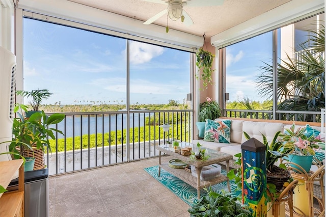 sunroom / solarium featuring ceiling fan and a water view