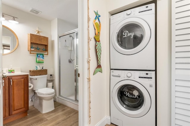 washroom with stacked washer / dryer and light hardwood / wood-style flooring