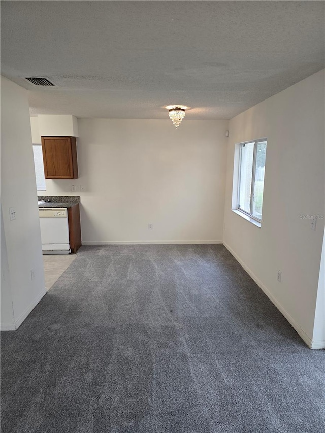 unfurnished living room featuring carpet floors, a textured ceiling, and a chandelier