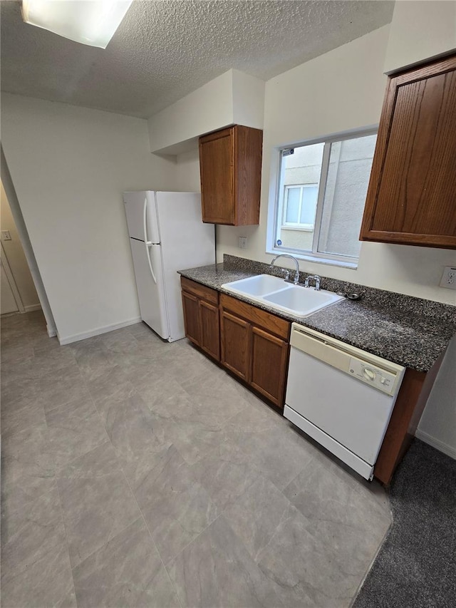 kitchen featuring a textured ceiling, white appliances, and sink