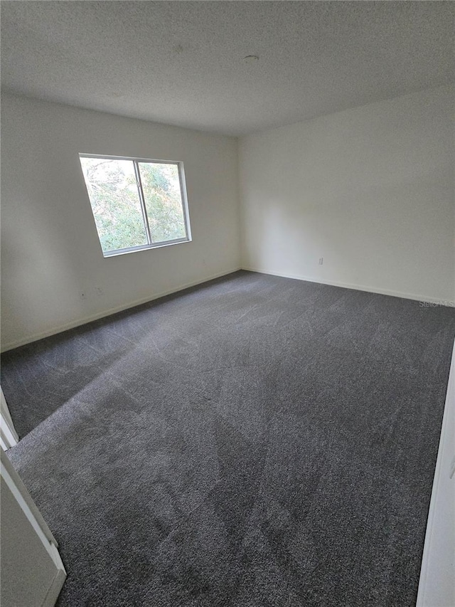 carpeted empty room featuring a textured ceiling