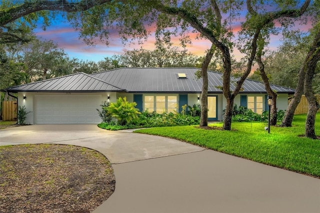 ranch-style house featuring a garage and a yard