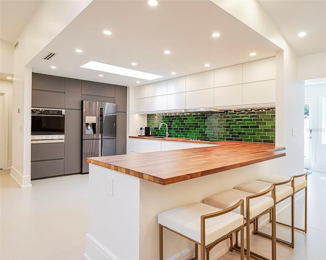 kitchen featuring stainless steel appliances, white cabinetry, and a kitchen breakfast bar