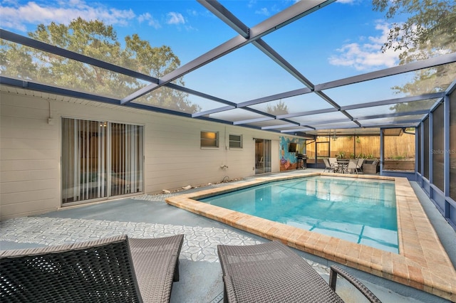 view of pool with glass enclosure and a patio area