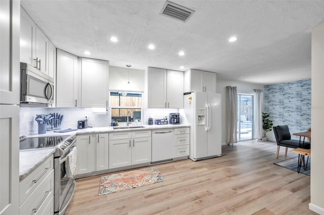 kitchen featuring sink, stainless steel appliances, backsplash, a textured ceiling, and white cabinets