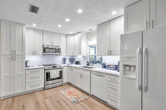 kitchen featuring pendant lighting, white cabinetry, sink, and appliances with stainless steel finishes