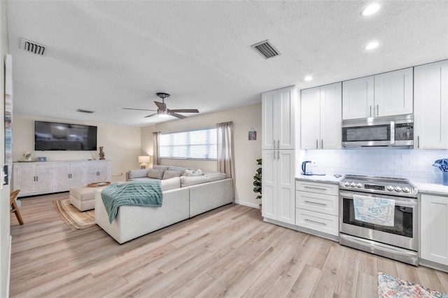 kitchen with stainless steel appliances, tasteful backsplash, light hardwood / wood-style flooring, a textured ceiling, and white cabinets