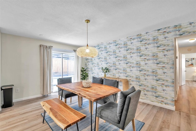 dining area with a textured ceiling and light hardwood / wood-style floors