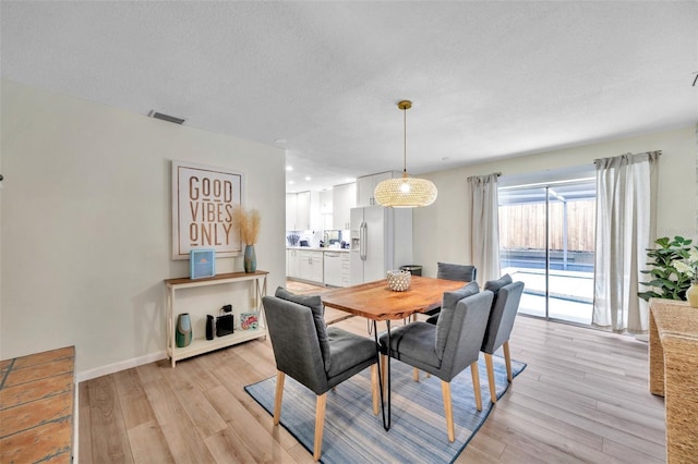 dining area featuring light wood-type flooring and a textured ceiling