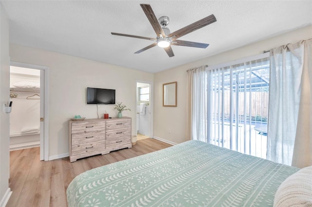 bedroom featuring light wood-type flooring, access to outside, ceiling fan, a spacious closet, and connected bathroom