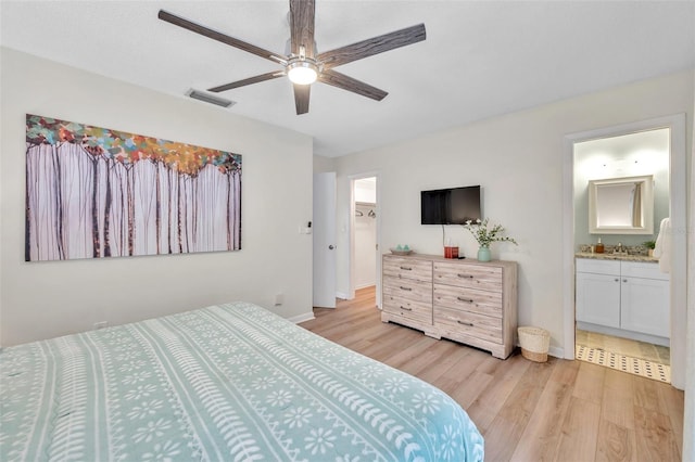 bedroom featuring connected bathroom, light hardwood / wood-style floors, and ceiling fan