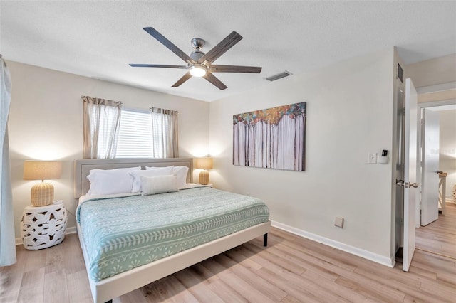 bedroom with a textured ceiling, light hardwood / wood-style floors, and ceiling fan