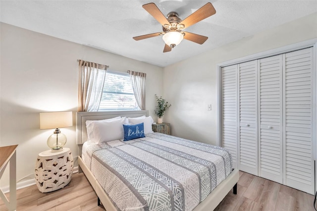 bedroom with a textured ceiling, light wood-type flooring, a closet, and ceiling fan