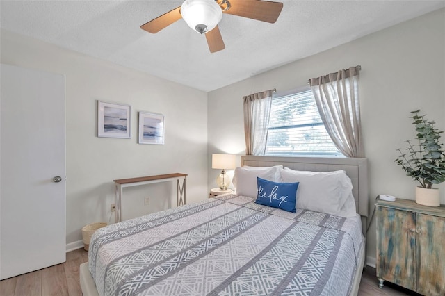 bedroom with hardwood / wood-style flooring, ceiling fan, and a textured ceiling