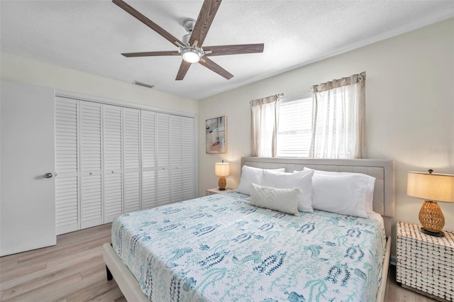 bedroom featuring a closet, ceiling fan, light hardwood / wood-style flooring, and a textured ceiling